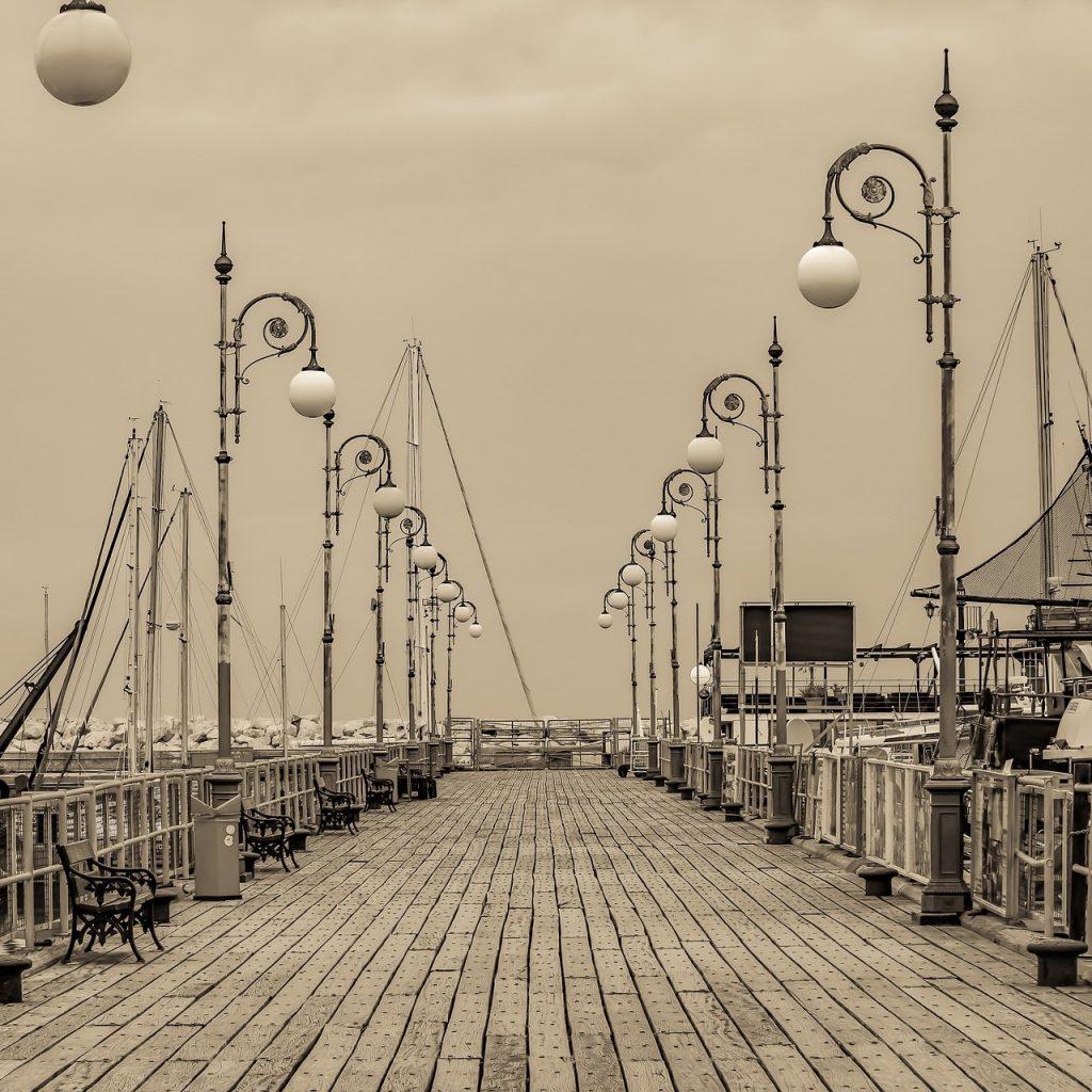 Decked marina leading to the sea, lined with old-fashioned lamps. Sepia tone. Larnaca Marina, Cyprus.