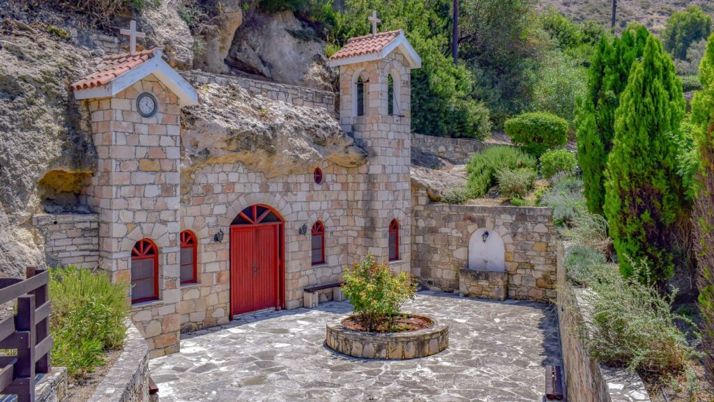 Photo of little church built into a cave, stone-built with little courtyard.